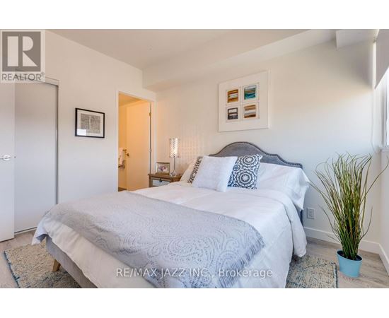 A bedroom with a large bed and a potted plant.
