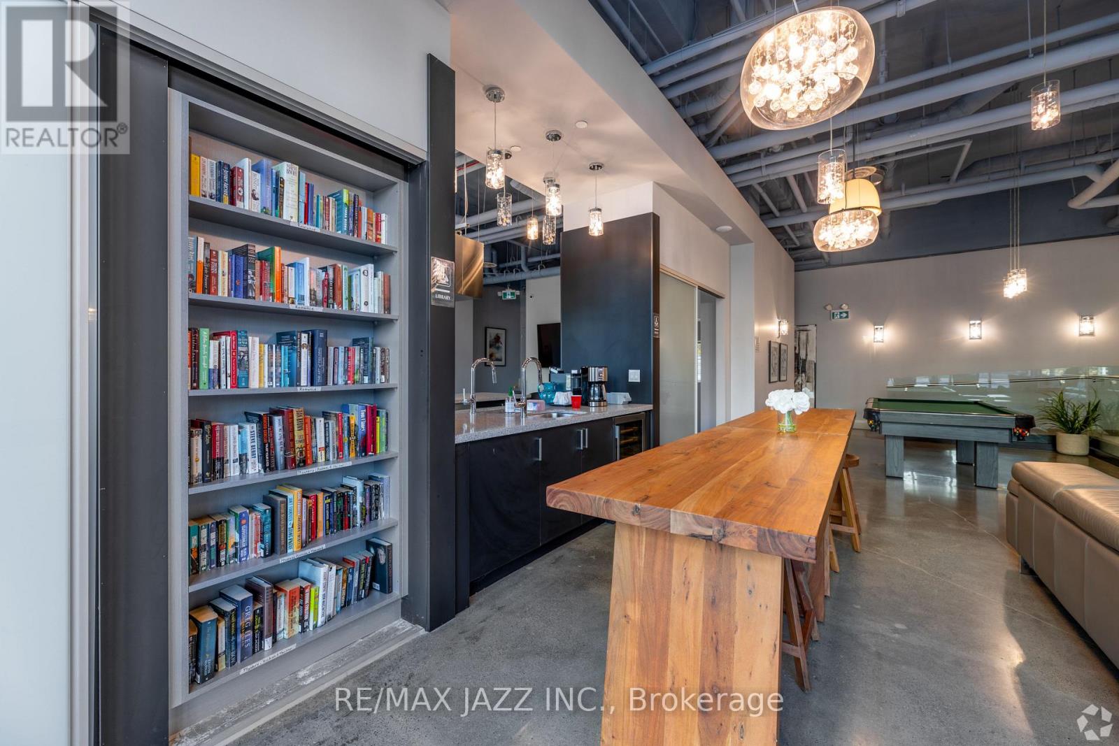 A modern living room with a wooden table and a bookshelf filled with books.