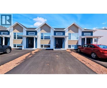 A real estate sign is displayed in front of a building with multiple garage doors.
