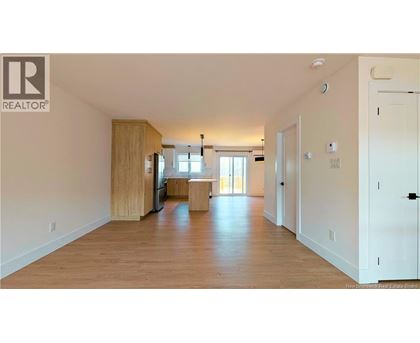 A spacious living room with wooden floors and white walls.