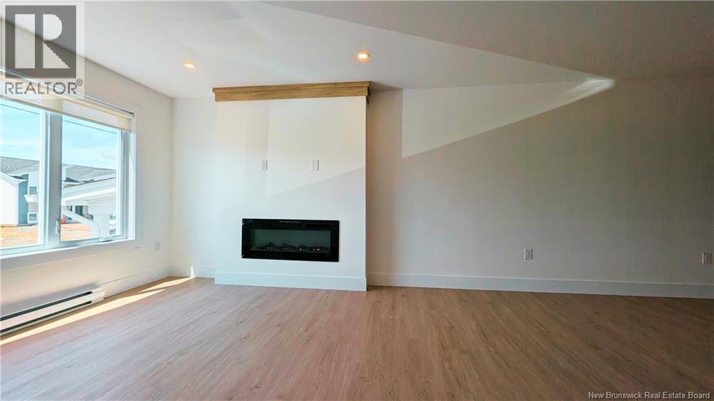 A large, empty room with a fireplace and wooden flooring.