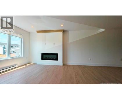 A large, empty room with a fireplace and wooden flooring.