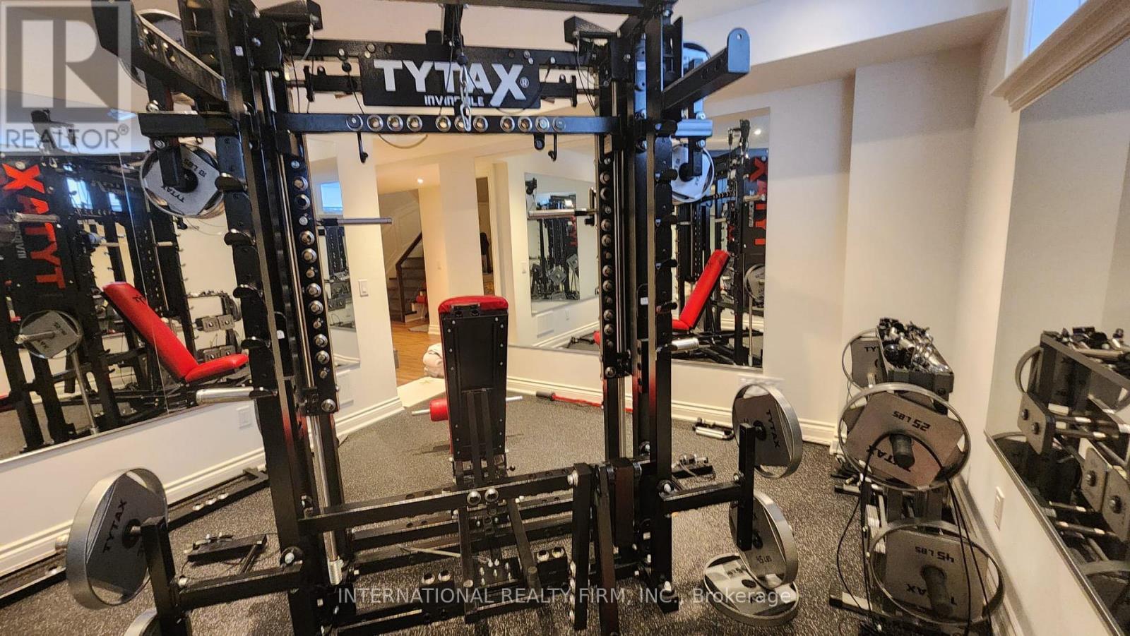 A gym with a Tytan X squat rack and weights.
