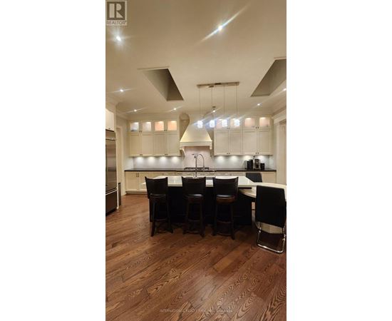 A modern kitchen with a dark wood floor and white cabinets.