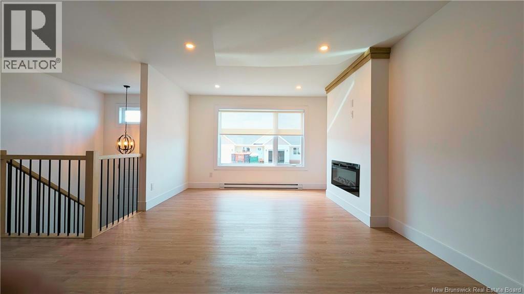 A spacious living room with a staircase on the left and a large window on the right.