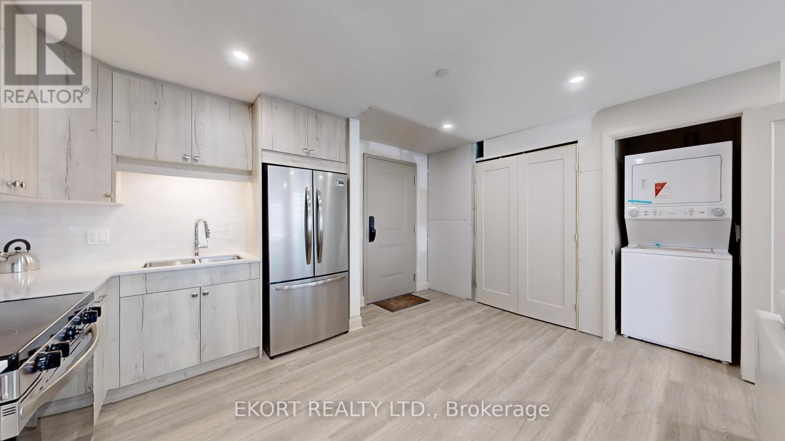 A kitchen with white cabinets and a stainless steel refrigerator.