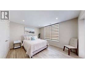 A bedroom with a large bed, a nightstand, a chair, and a painting on the wall.