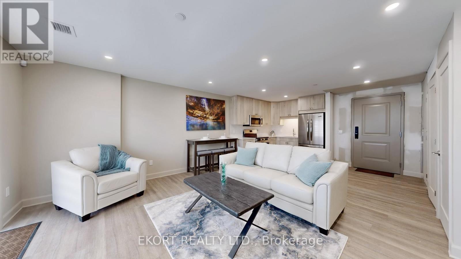 A living room with a white couch, a coffee table, and a painting on the wall.