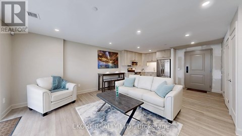 A living room with a white couch, a coffee table, and a painting on the wall.