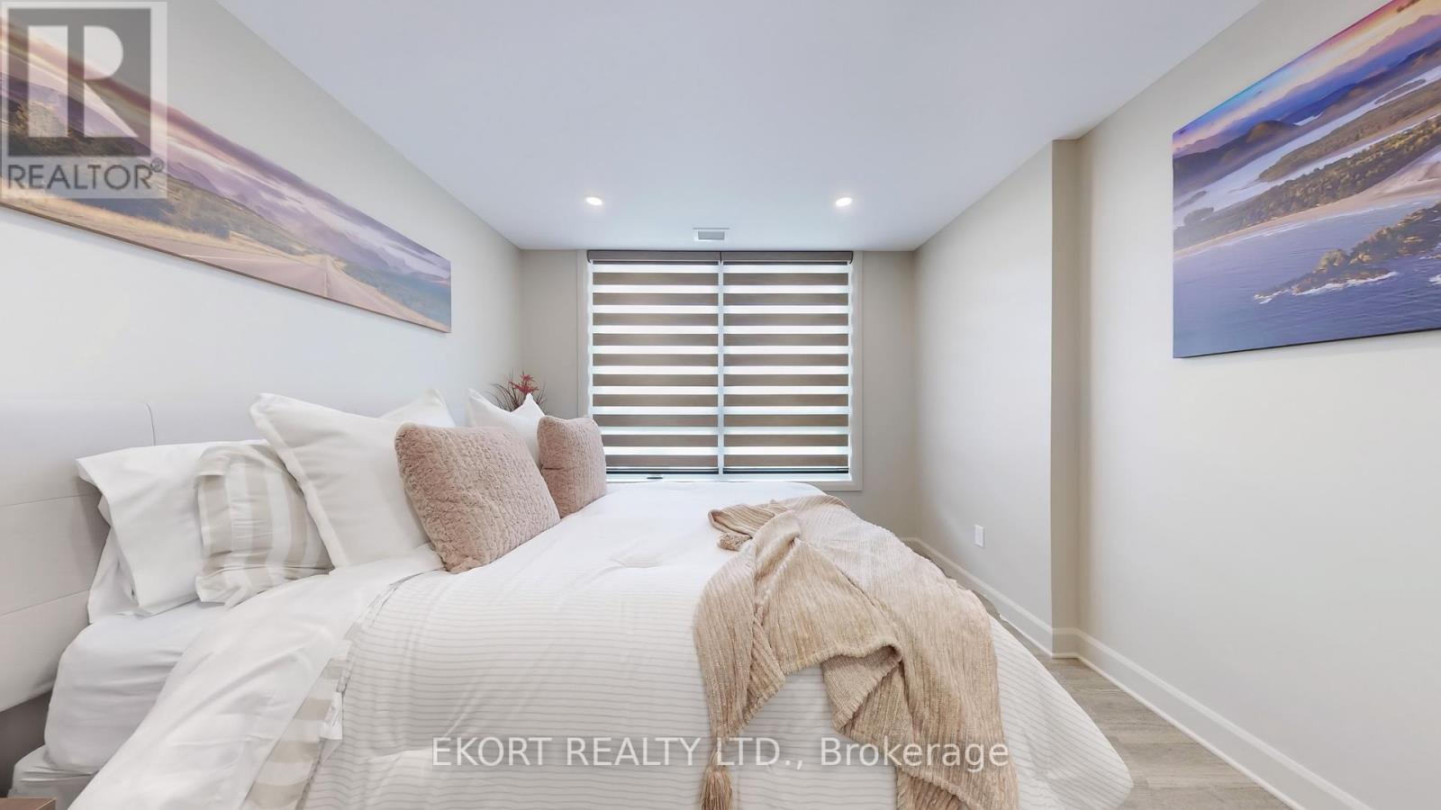 A bedroom with a bed, pillows, and a blanket with a window in the background.