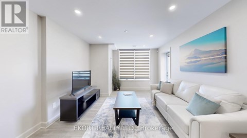 A living room with a white couch, a television, and a painting on the wall.