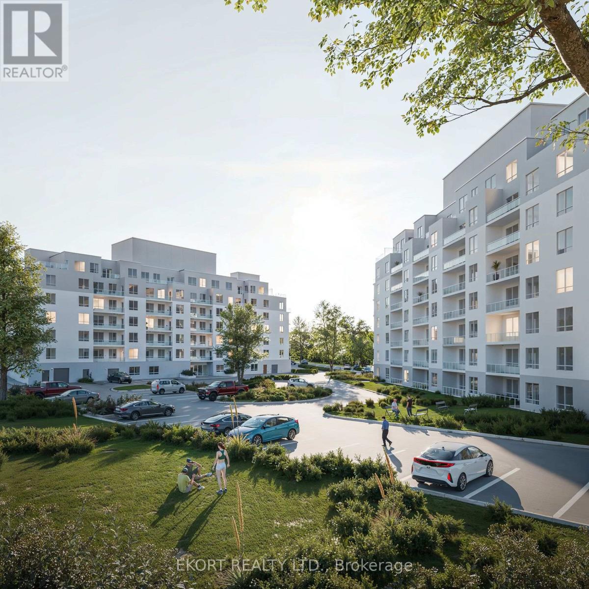 A modern apartment complex with cars parked in the driveway and people walking around.