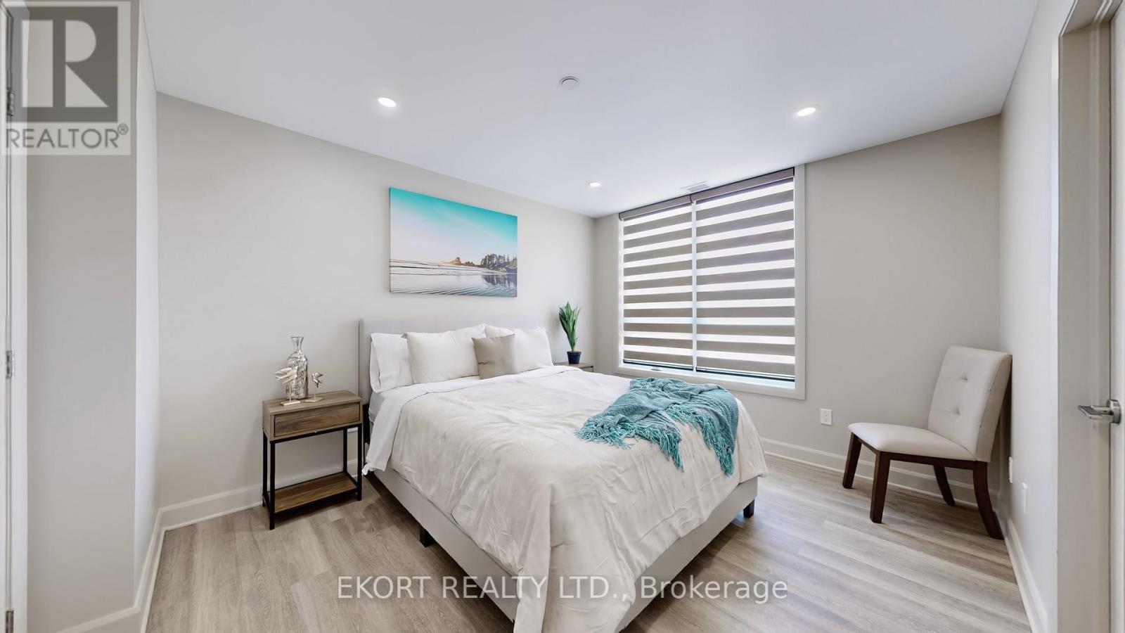 A bedroom with a bed, nightstand, and chair.