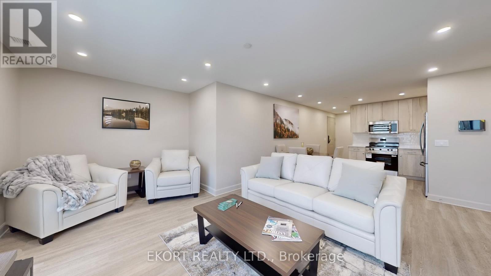 A living room with white furniture and a painting on the wall.
