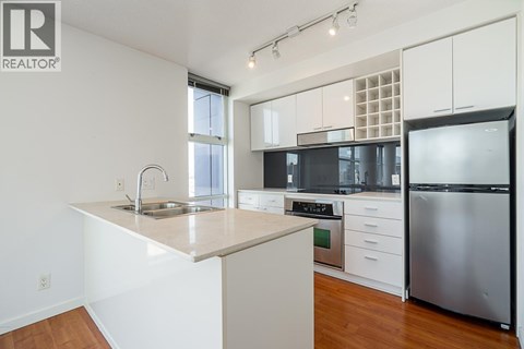 A kitchen with white cabinets and a stainless steel refrigerator.