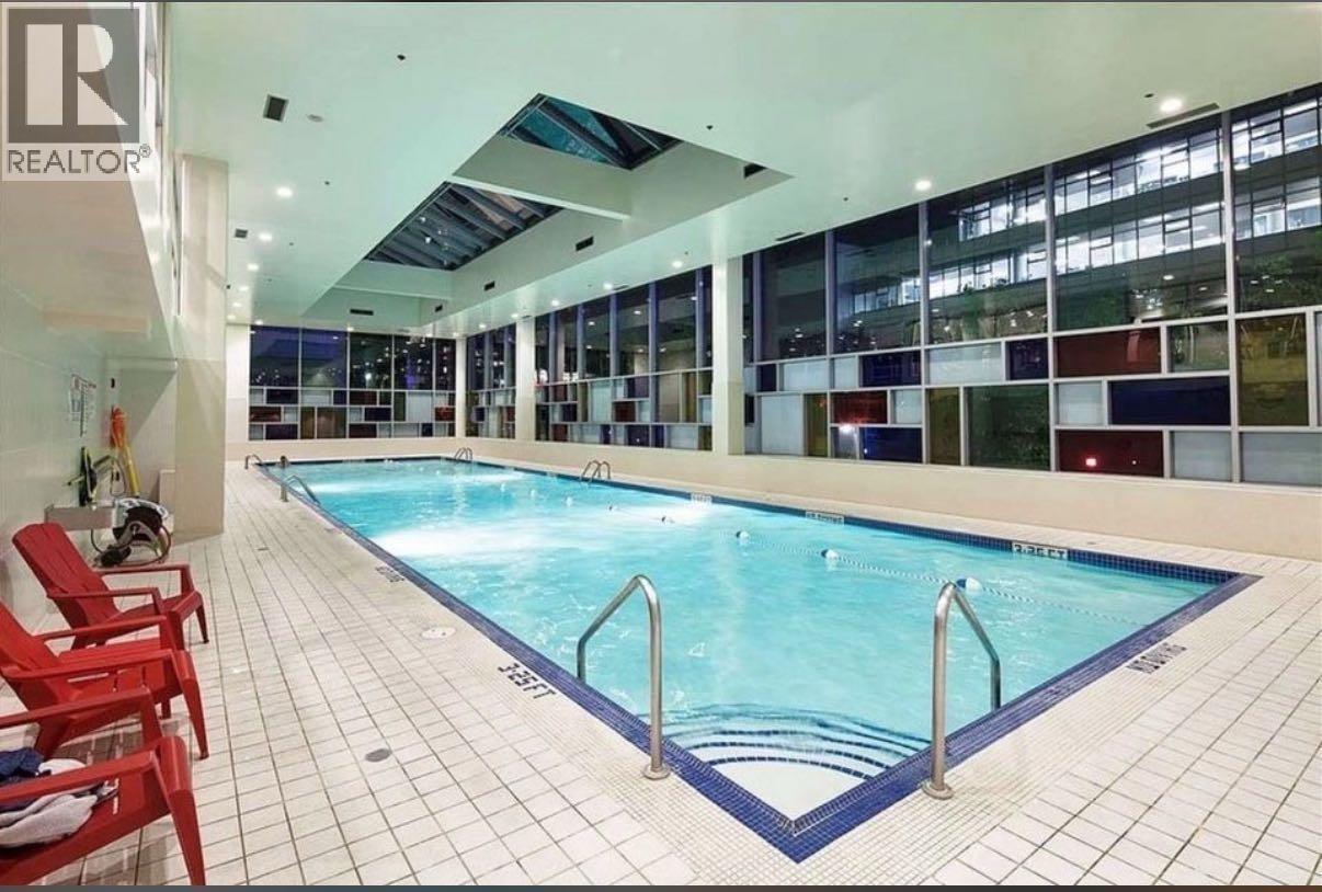 A swimming pool inside a building with a glass wall.