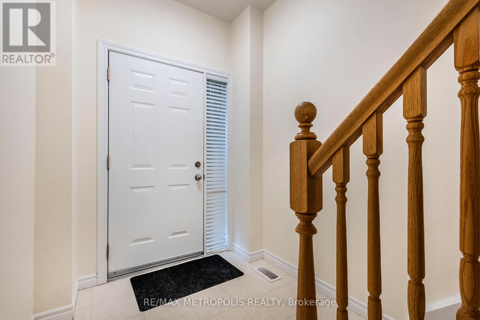 A white door with a black mat in front of a wooden staircase.