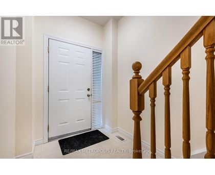 A white door with a black mat in front of a wooden staircase.