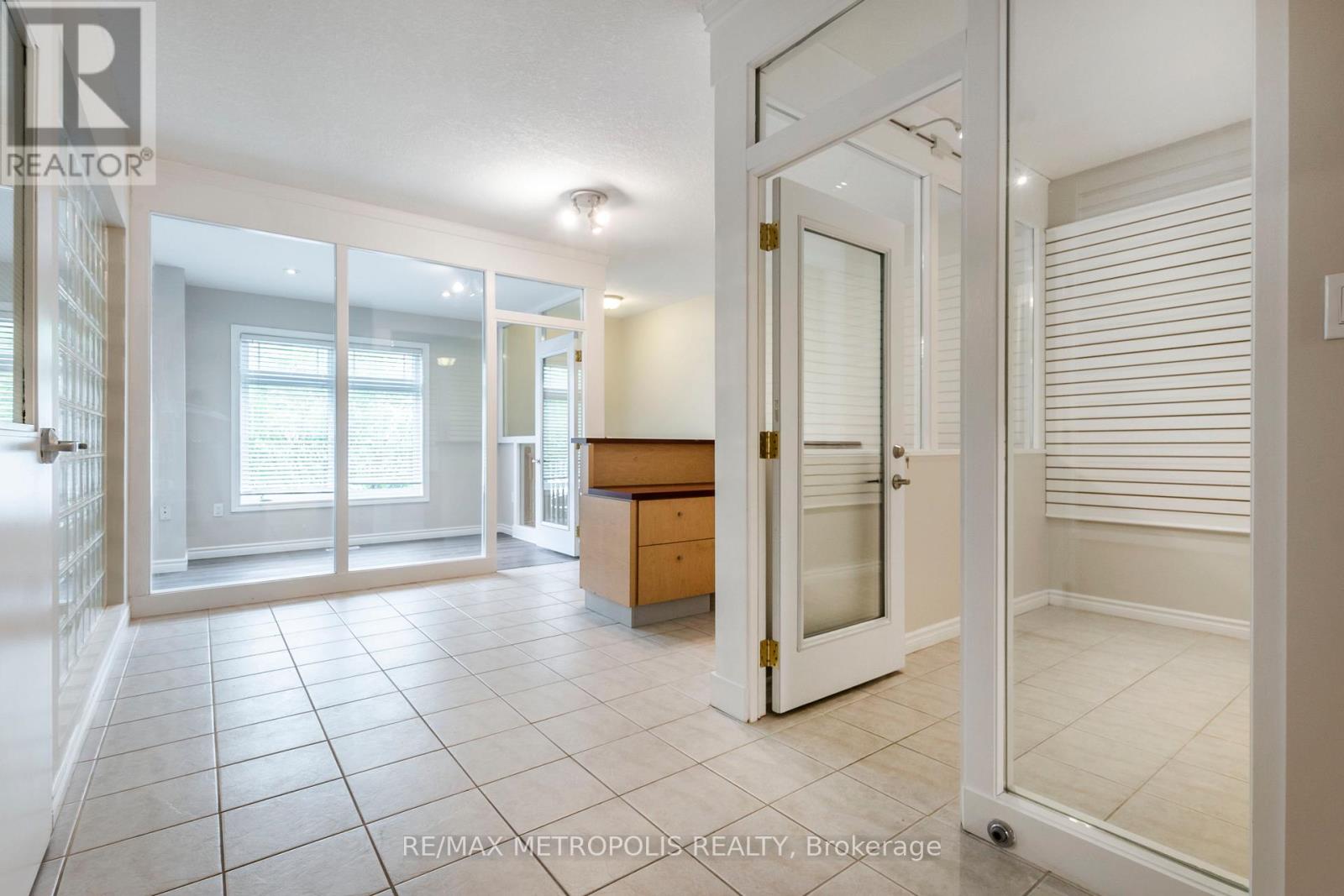 A spacious room with a white door and a tiled floor.