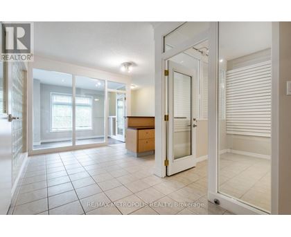 A spacious room with a white door and a tiled floor.
