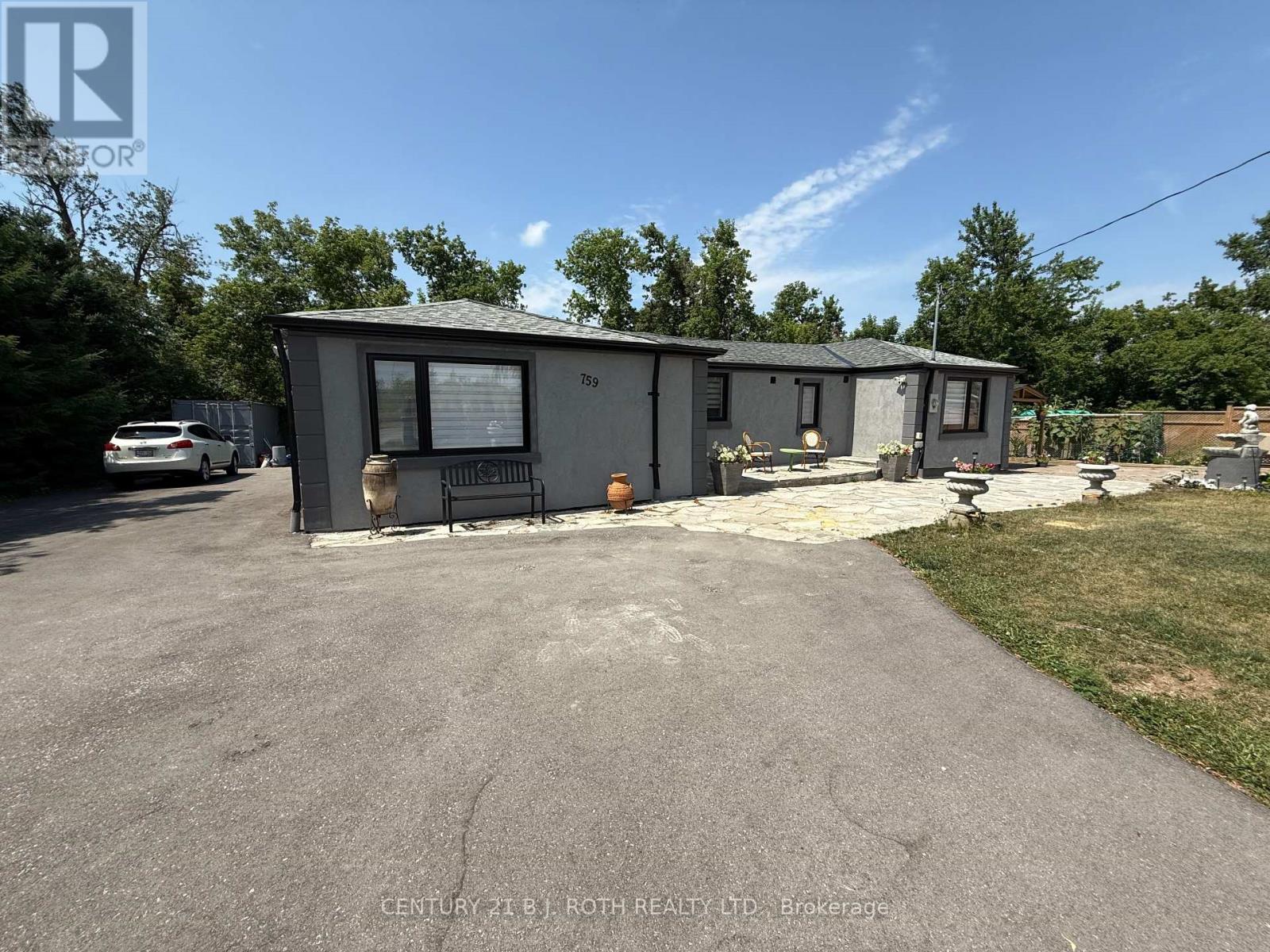 A grey building with a sign that says "Century 21 B.J. Roth Realty LTD Brokerage" in front of it.