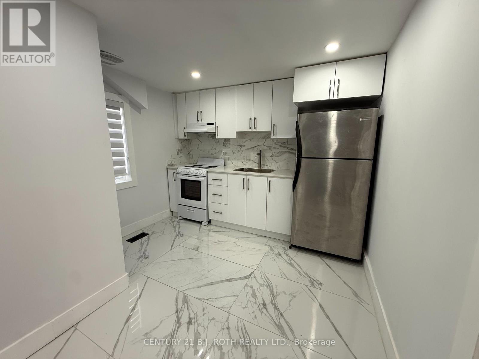 A kitchen with white cabinets and a marble floor.