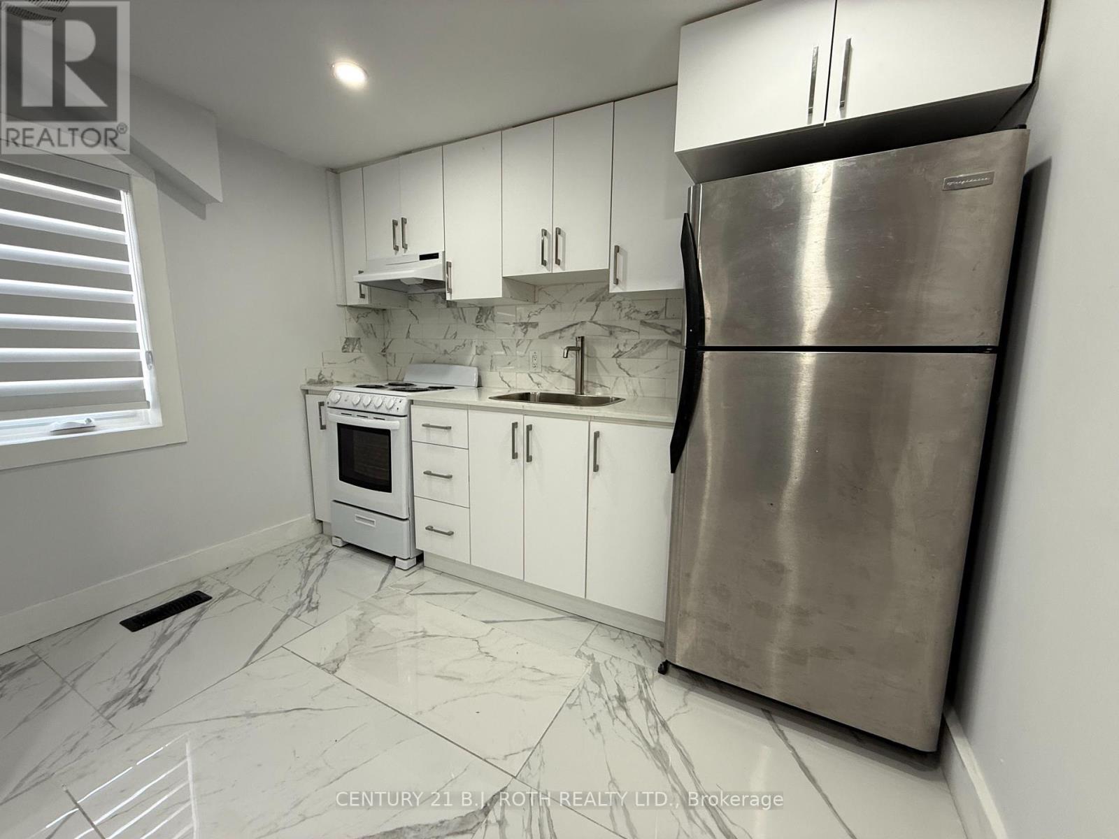 A kitchen with white cabinets and a marble floor.