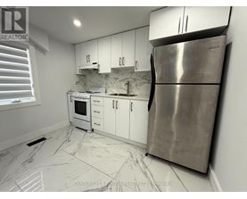 A kitchen with white cabinets and a marble floor.