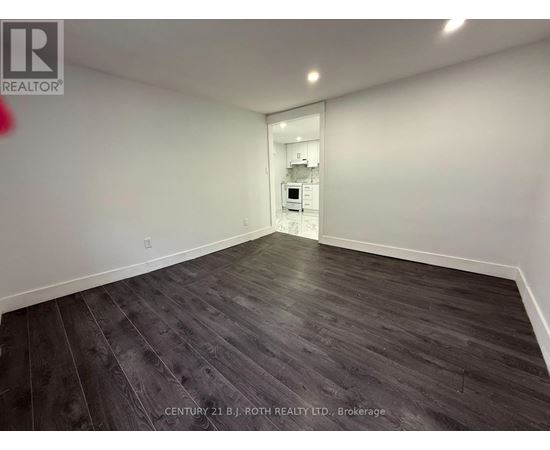A spacious room with wooden flooring and a white wall.
