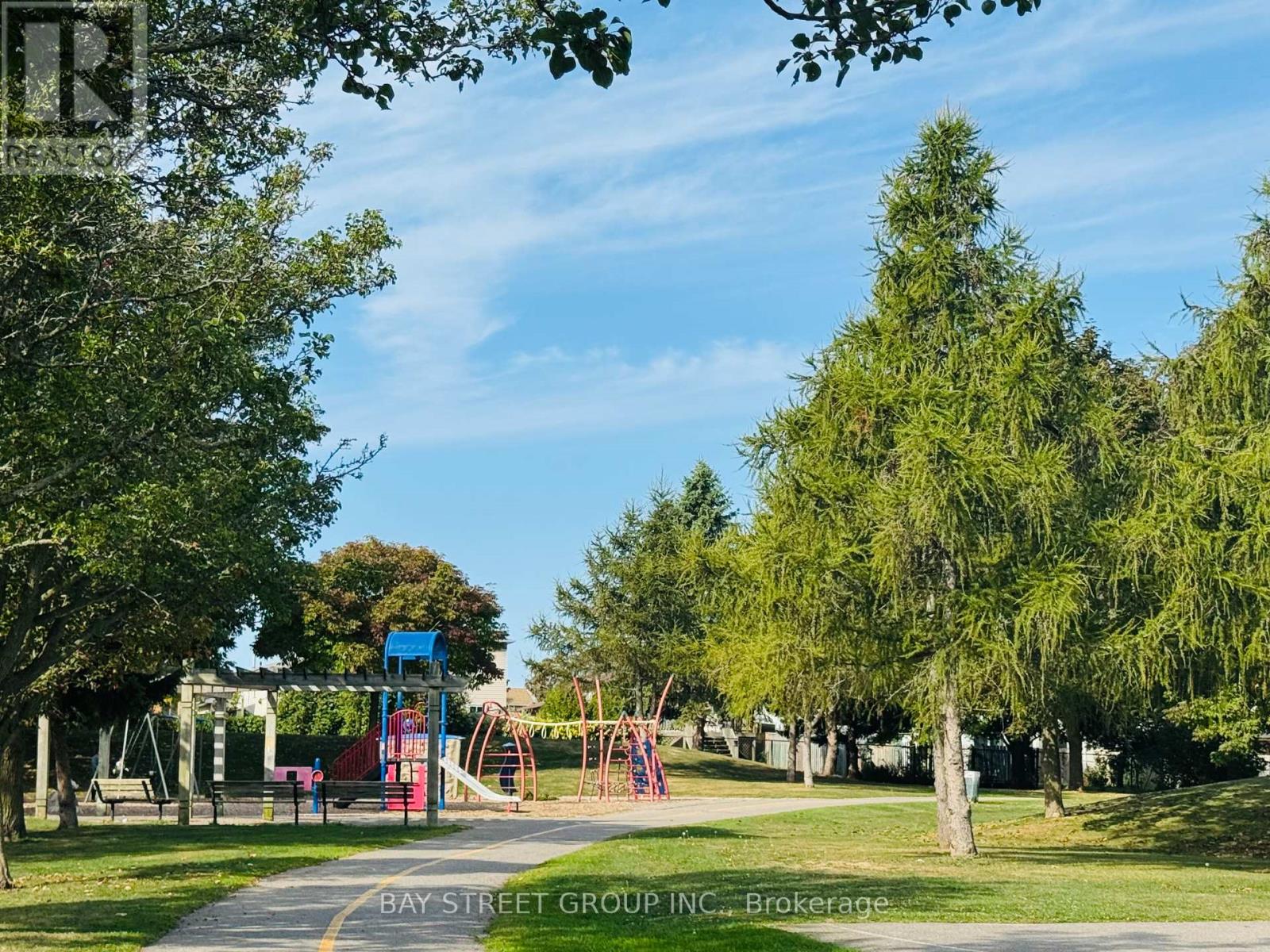 A playground with a slide and swings is surrounded by trees.
