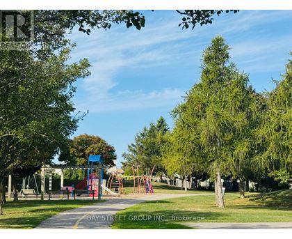 A playground with a slide and swings is surrounded by trees.