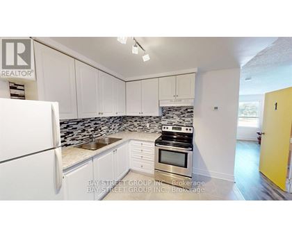 A kitchen with white cabinets and a black and white tiled backsplash.