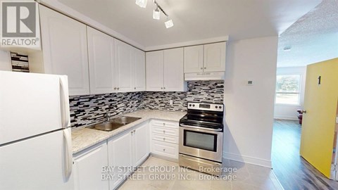 A kitchen with white cabinets and a black and white tiled backsplash.