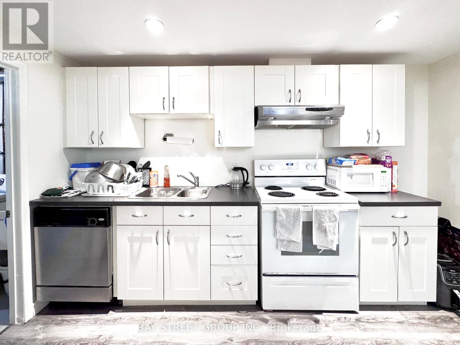 A white kitchen with a black counter top and a sink.