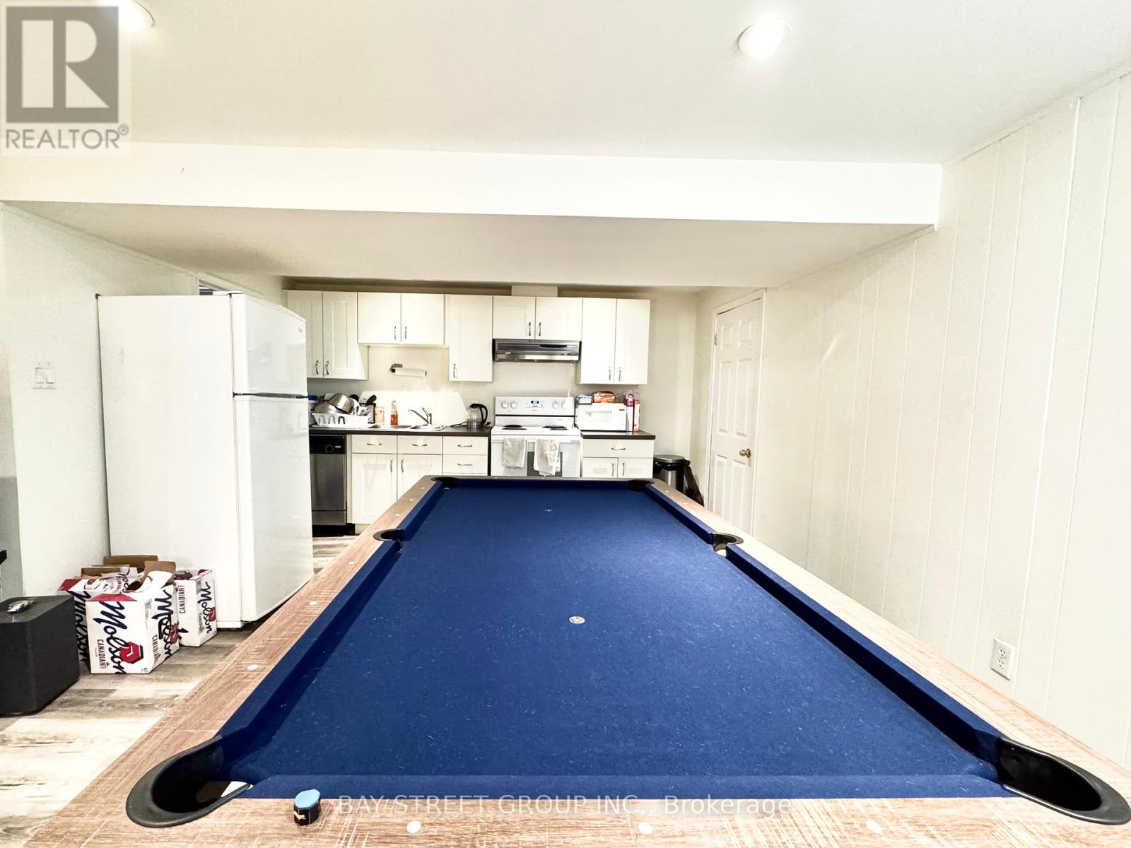 A pool table in a room with a refrigerator and cabinets.