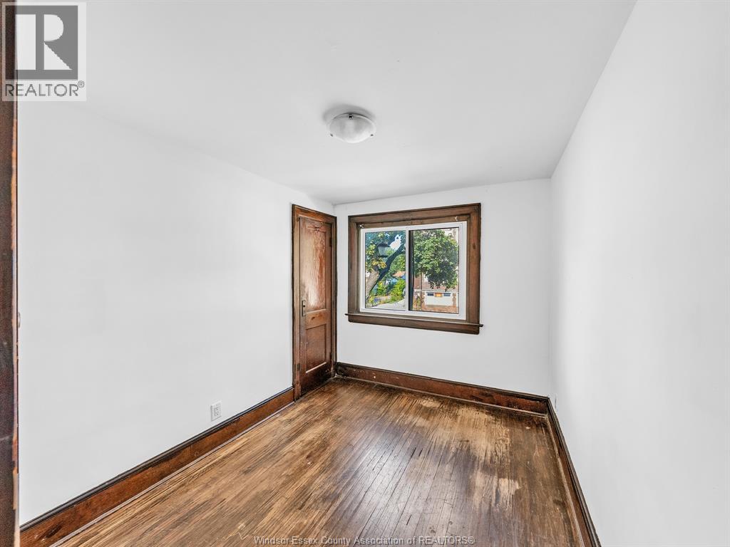 A room with a wooden floor and a window with a view of trees.