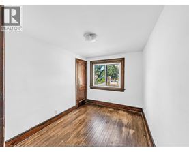 A room with a wooden floor and a window with a view of trees.