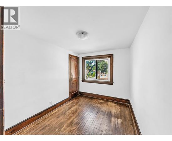 A room with a wooden floor and a window with a view of trees.