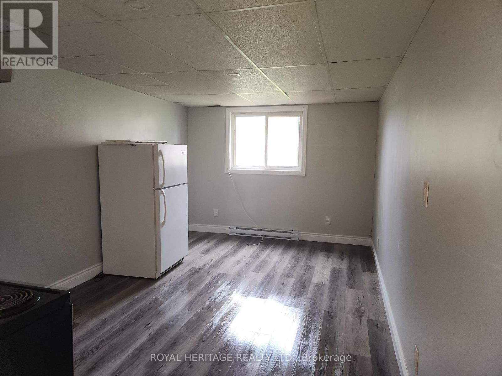 A white refrigerator in a room with a window and wooden flooring.
