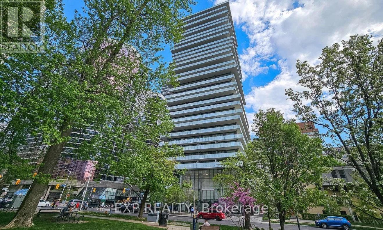 A tall building with a striped facade stands in a park with trees and people walking around.