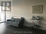 A living room with a grey couch and a small table with bottles on it.