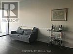 A living room with a grey couch and a small table with bottles on it.