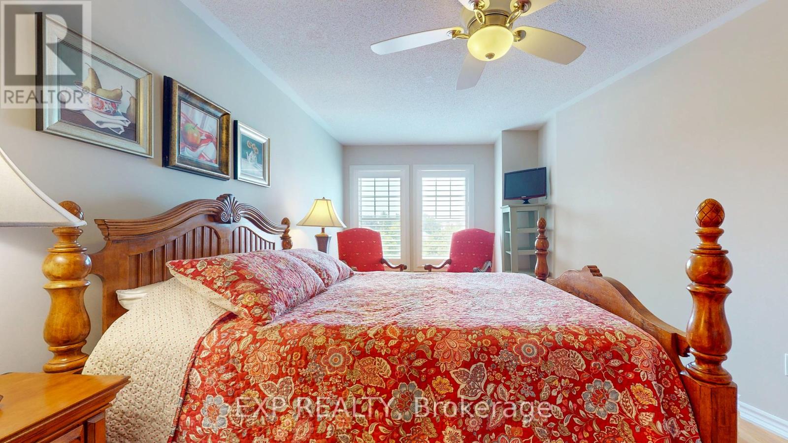 A bedroom with a bed in the center and a ceiling fan above it.