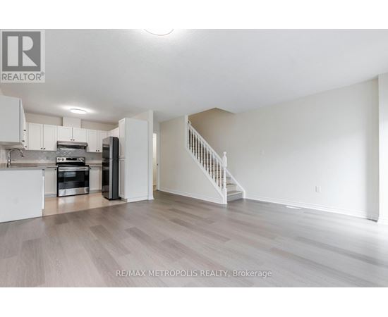 A spacious kitchen with white cabinets and a staircase leading to the upper floor.