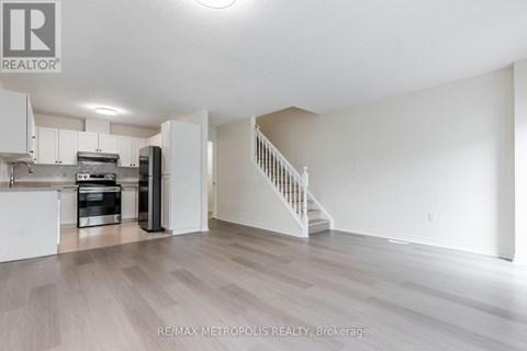 A spacious kitchen with white cabinets and a staircase leading to the upper floor.