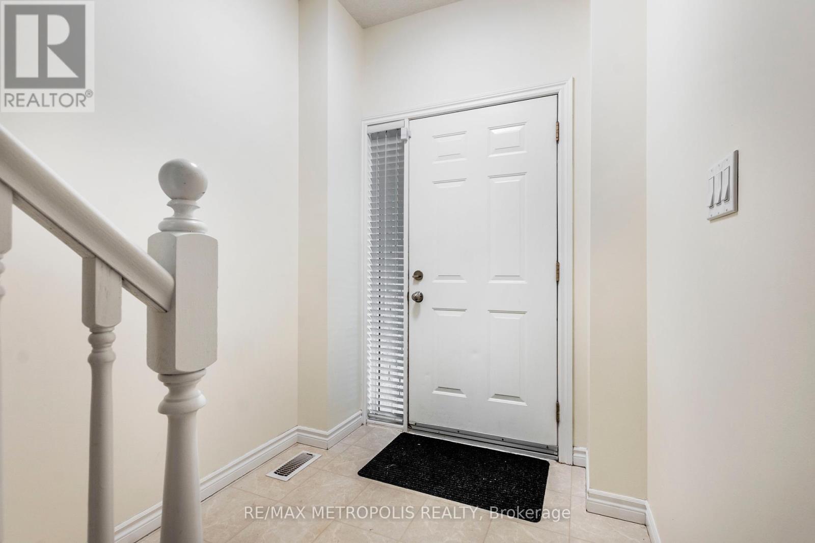 A white door is in a hallway with a black doormat.