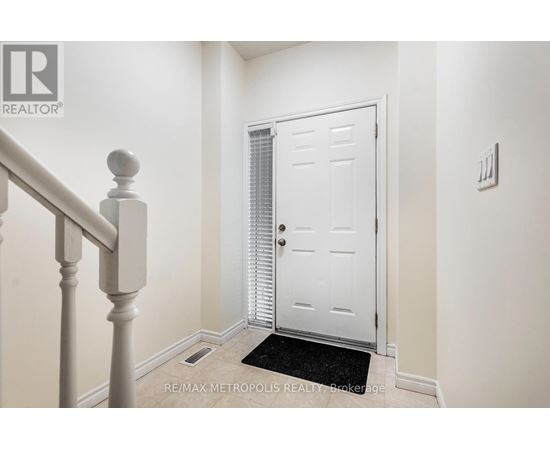 A white door is in a hallway with a black doormat.
