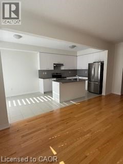 A kitchen with a refrigerator, sink, and stove.