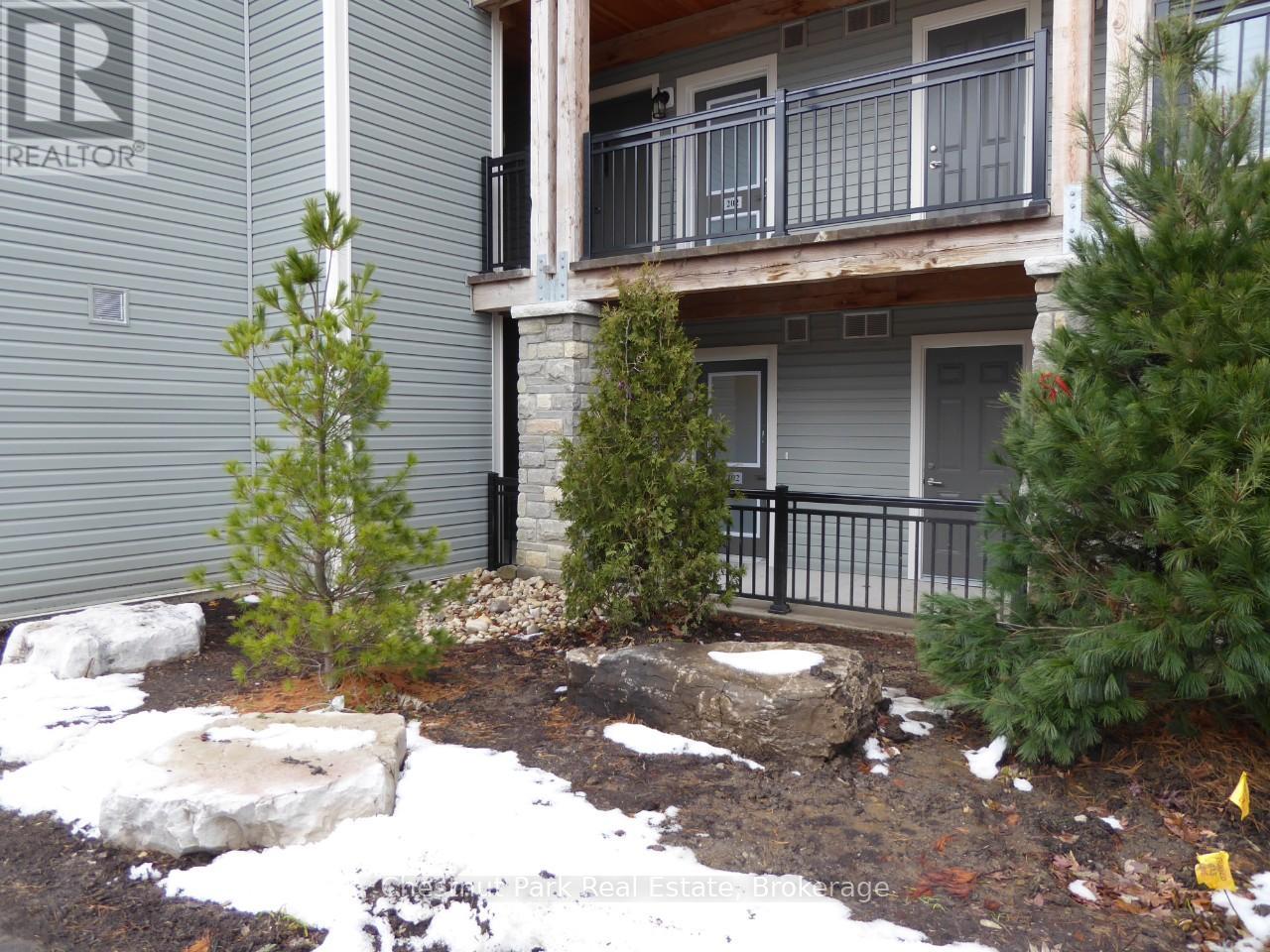 A small tree is in the front yard of a house with a balcony.
