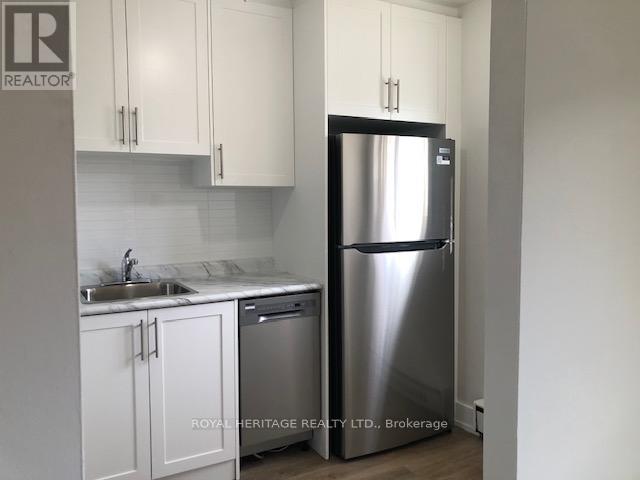 A kitchen with white cabinets and a stainless steel refrigerator.